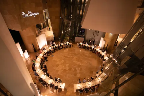 Dom Pérignon Révélations 2026: round dinner table seen from above, guests in candlelight beneath the Dom Pérignon lettering