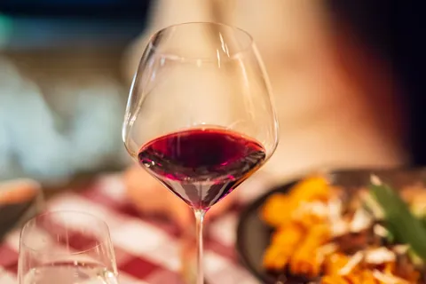 RIEDEL red wine glass on a dinner table, a plate of pasta beside it